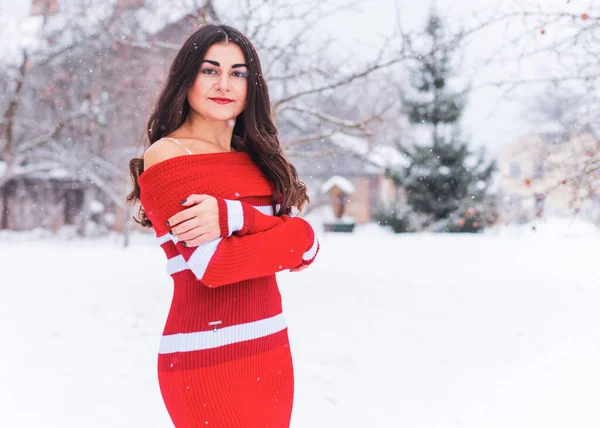 Karlı kış gününde siyah saçlı, örgü kırmızısı elbiseli İspanyol bir kadın. Sıradan moda anlayışı.