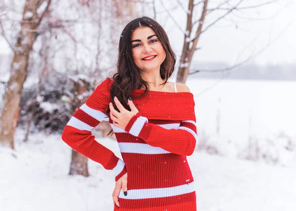 Karlı kış gününde siyah saçlı, örgü kırmızısı elbiseli İspanyol bir kadın. Sıradan moda anlayışı.