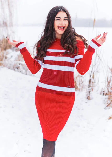 Karlı kış gününde siyah saçlı, örgü kırmızısı elbiseli İspanyol bir kadın. Sıradan moda anlayışı.