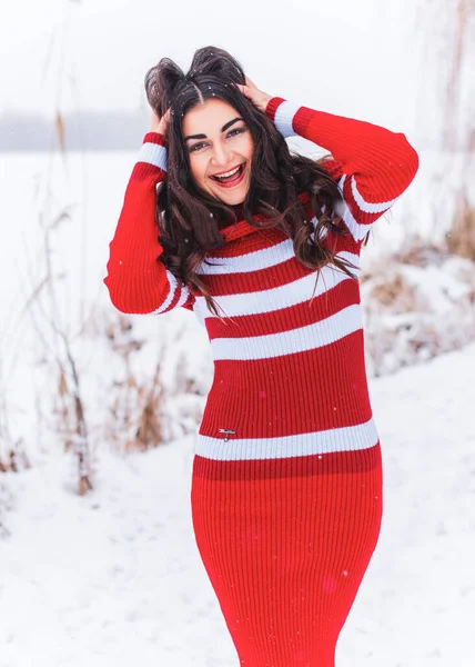 Karlı kış gününde siyah saçlı, örgü kırmızısı elbiseli İspanyol bir kadın. Sıradan moda anlayışı.