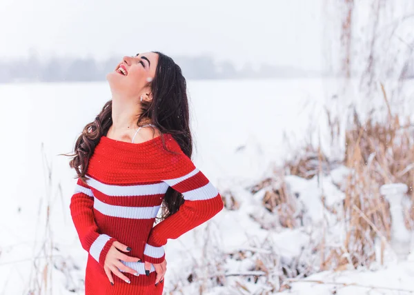 Karlı kış gününde siyah saçlı, örgü kırmızısı elbiseli İspanyol bir kadın. Sıradan moda anlayışı.