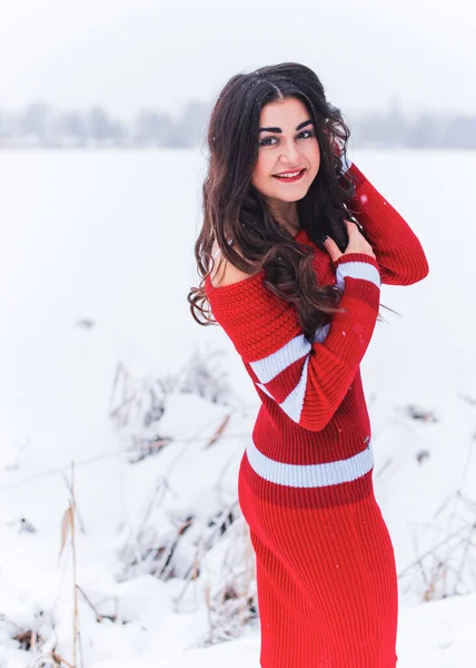 Karlı kış gününde siyah saçlı, örgü kırmızısı elbiseli İspanyol bir kadın. Sıradan moda anlayışı.