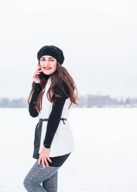 Sokakta poz veren güzel bir kadının açık hava portresi. Siyah bere takan ve örgü ören bir manken. Kadın moda konsepti