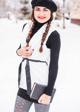 Sokakta poz veren güzel bir kadının açık hava portresi. Siyah bere takan ve örgü ören bir manken. Kadın moda konsepti