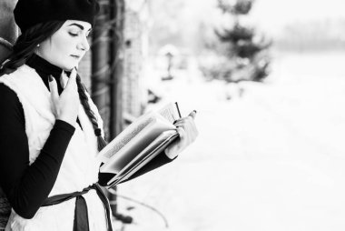 Sokakta poz veren güzel bir kadının açık hava portresi. Siyah bere takan ve örgü ören bir manken. Kadın moda konsepti