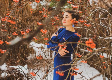 Karlı bir bahçede, uzun mavi elbiseli zarif bir Arap kadın. Kadınlık kavramı ve hanımefendinin zarafeti