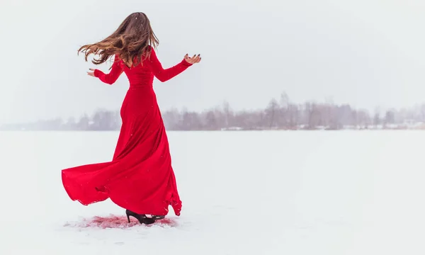 雪の日の絹のドレスで踊るヒスパニック系の女性 芸術的な赤い流れるガウンを振って 布をなびかせ 情熱の概念 — ストック写真