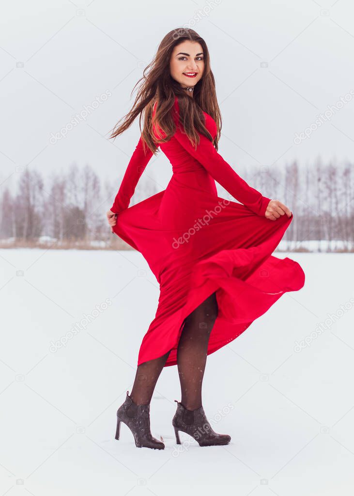 Hispanic woman dancing in silk dress at snowy day, artistic red flowing gown waving and fluttering fabric, Passion concept