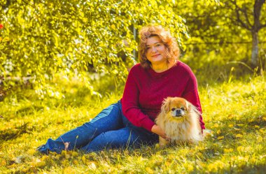 Şehir parkında, tombul, güneşli, sıcacık elbiseli bir kadın. Büyük bedenli bayanlar için kıyafetler.