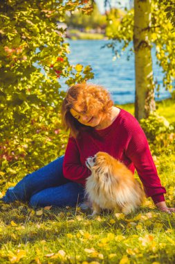Şehir parkında, tombul, güneşli, sıcacık elbiseli bir kadın. Büyük bedenli bayanlar için kıyafetler.