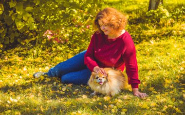 Şehir parkında, tombul, güneşli, sıcacık elbiseli bir kadın. Büyük bedenli bayanlar için kıyafetler.