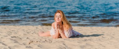 Plajda pembe romantik, yumuşak, uzun elbiseli bir kadın, güneşli sıcak bir gün. Rahatla ve özgürlük kavramı 