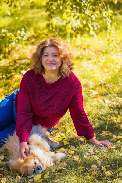 Küçük altın köpeği olan hoş bir bayan, evcil hayvan konsepti, köpek en iyi insan dostudur.