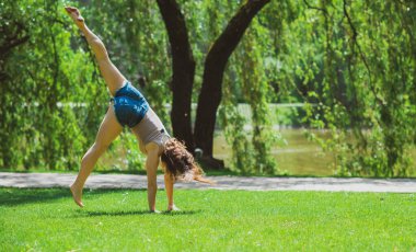 Mutlu kadın hayatın tadını çıkarıyor, eğleniyor ve şehir parkında jimnastik yapıyor. Yaz güneşli günler ve keyifli günler.