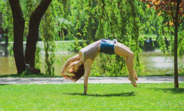 Mutlu kadın hayatın tadını çıkarıyor, eğleniyor ve şehir parkında jimnastik yapıyor. Yaz güneşli günler ve keyifli günler.
