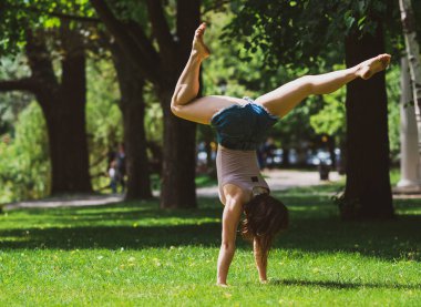 Mutlu kadın hayatın tadını çıkarıyor, eğleniyor ve şehir parkında jimnastik yapıyor. Yaz güneşli günler ve keyifli günler.