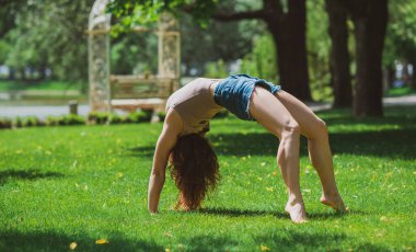 Mutlu kadın hayatın tadını çıkarıyor, eğleniyor ve şehir parkında jimnastik yapıyor. Yaz güneşli günler ve keyifli günler.