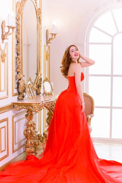 豪華な赤いドレスと豪華なアパートでポーズをとる貴重な宝石で壮大な若い女性 クラシックなヴィンテージインテリア 美人高級ファッション — ストック写真