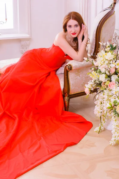 富丽堂皇的年轻女子穿着华丽的红色衣服 戴着贵重的珠宝 摆设在豪华的公寓里 经典的老式内饰 漂亮衣服时尚 — 图库照片