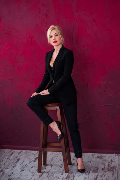 高いファッションショットのセクシーブロンド女性で黒スーツで赤背景 肖像画のエレガントな服を着て豪華なビジネス女性とともに赤唇 — ストック写真
