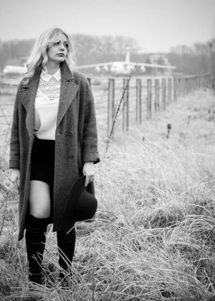 女性は早春の夢のような気分で空港近くを歩き ウールのオーバーサイズのスタイリッシュなコートを着て — ストック写真