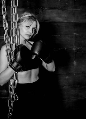 Kadın sert bir tekmeyle kum torbasına vuruyor. Formda kutu, dövüş sanatları ve spor kavramı. Başarı için savaşıyor..