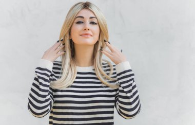 60 'lar-70' ler görünüşü. Sarışın kadın makyaj malzemesi çizgili kazak, modaya uygun bir konsept.