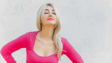 Klasik kız pembe tonlu Barbie bebeğe benziyor. Sarışın kadın makyaj malzemesi pembe kazak giyer, şık bir konsept.