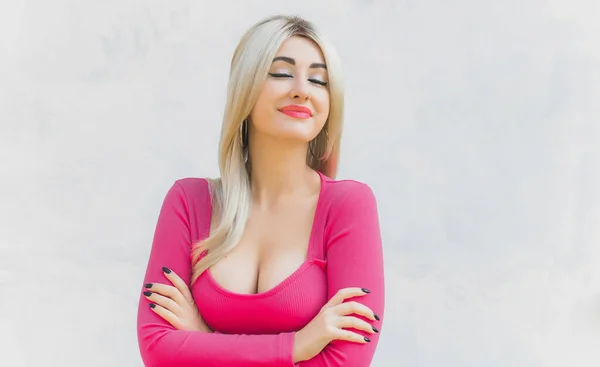 Linda jovem modelo de mulher com rosto de boneca com maquiagem de moda em  vestido rosa glamoroso posando em fundo rosa