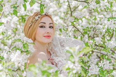 Bahar bahçesinde gelin. Makyajlı ve çiçekli romantik dantelli yarışçı kadın.