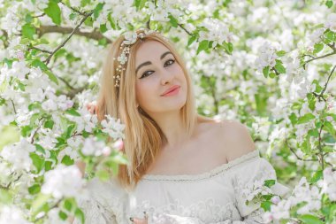 Bahar bahçesinde gelin. Makyajlı ve çiçekli romantik dantelli yarışçı kadın.