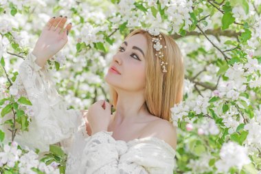 Bahar bahçesinde gelin. Makyajlı ve çiçekli romantik dantelli yarışçı kadın.