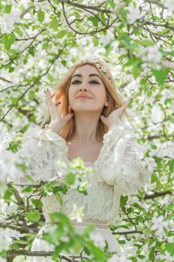 Bahar bahçesinde gelin. Makyajlı ve çiçekli romantik dantelli yarışçı kadın.