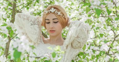 Bahar bahçesinde gelin. Makyajlı ve çiçekli romantik dantelli yarışçı kadın.