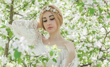 Bahar bahçesinde gelin. Makyajlı ve çiçekli romantik dantelli yarışçı kadın.