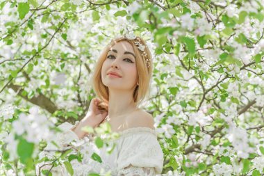 Bahar bahçesinde gelin. Makyajlı ve çiçekli romantik dantelli yarışçı kadın.