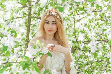 Bahar bahçesinde gelin. Makyajlı ve çiçekli romantik dantelli yarışçı kadın.