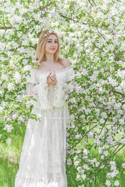 Bahar bahçesinde gelin. Makyajlı ve çiçekli romantik dantelli yarışçı kadın.