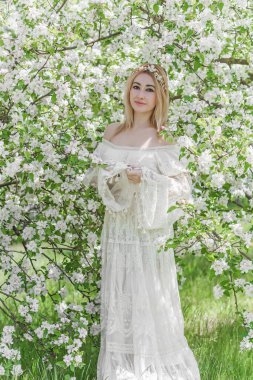 Bahar bahçesinde gelin. Makyajlı ve çiçekli romantik dantelli yarışçı kadın.