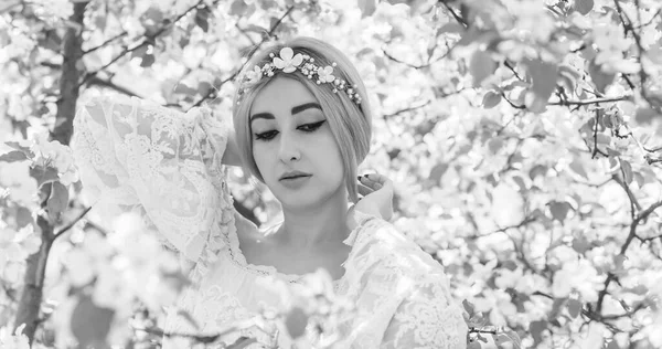 Bahar bahçesinde gelin. Makyajlı ve çiçekli romantik dantelli yarışçı kadın.