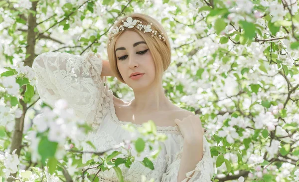 Bahar bahçesinde gelin. Makyajlı ve çiçekli romantik dantelli yarışçı kadın.