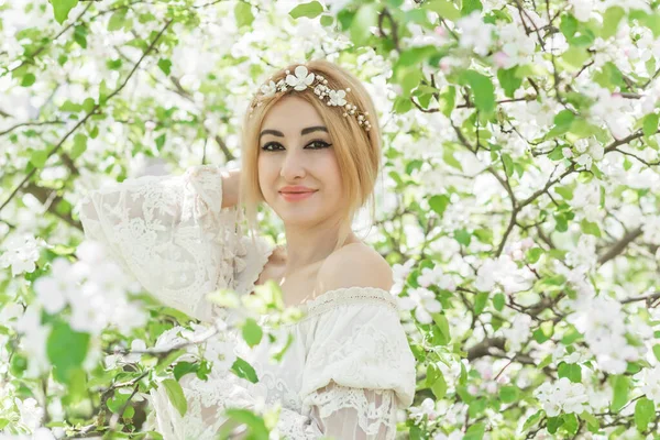 Bahar bahçesinde gelin. Makyajlı ve çiçekli romantik dantelli yarışçı kadın.