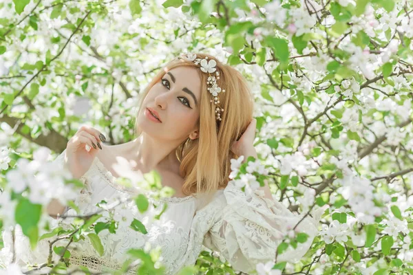 Bahar bahçesinde gelin. Makyajlı ve çiçekli romantik dantelli yarışçı kadın.
