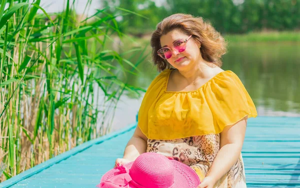 Plus size European or American woman at nature in yellow romantic dress and pink hat, enjoy the holidays. Life of people xl size, happy nice natural beauty woman. Concept of overweight