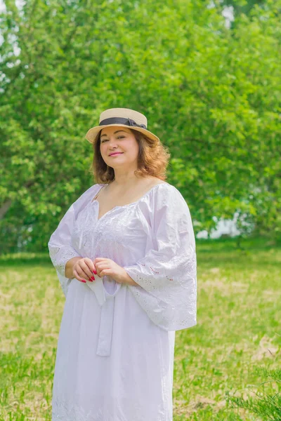 Plus size European or American woman at nature in yellow romantic dress and hat, enjoy the holidays. Life of people xl size, happy nice natural beauty woman. Concept of overweight