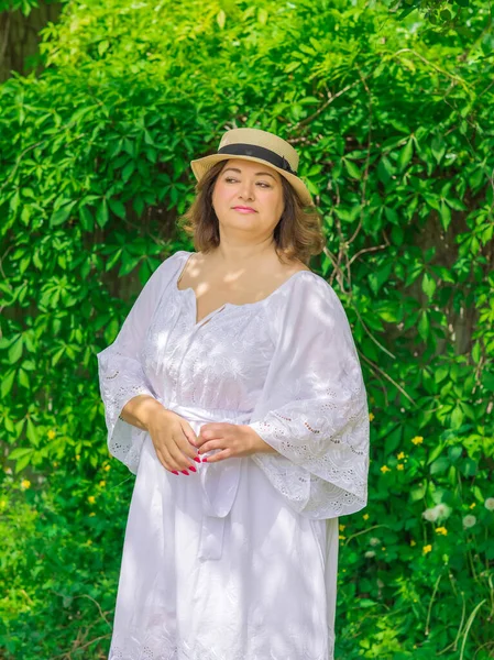 Plus size European or American woman at nature in yellow romantic dress and hat, enjoy the holidays. Life of people xl size, happy nice natural beauty woman. Concept of overweight