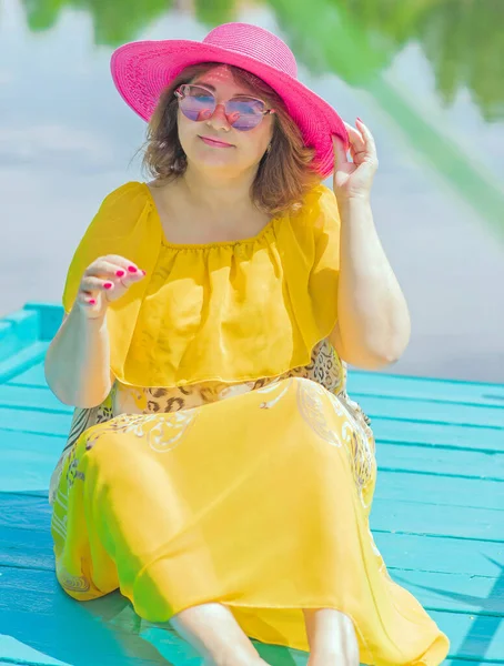 Plus size European or American woman at nature in yellow romantic dress and pink hat, enjoy the holidays. Life of people xl size, happy nice natural beauty woman. Concept of overweight