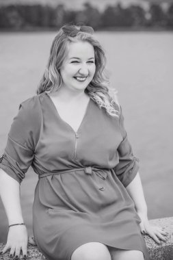 Büyük bedenli mutlu bir kadın, şehirde gezip hayatın tadını çıkarıyor. Aşırı kilolu genç bir bayan, şehir parkında şık giyinmiş. Doğal güzellik.