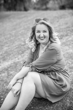 Büyük bedenli mutlu bir kadın, şehirde gezip hayatın tadını çıkarıyor. Aşırı kilolu genç bir bayan, şehir parkında şık giyinmiş. Doğal güzellik.