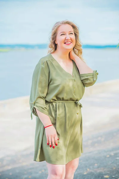 Happy woman of plus size, walks in the city enjoying life. Young lady with excess weight, stylishly dressed at the city park .Natural beauty